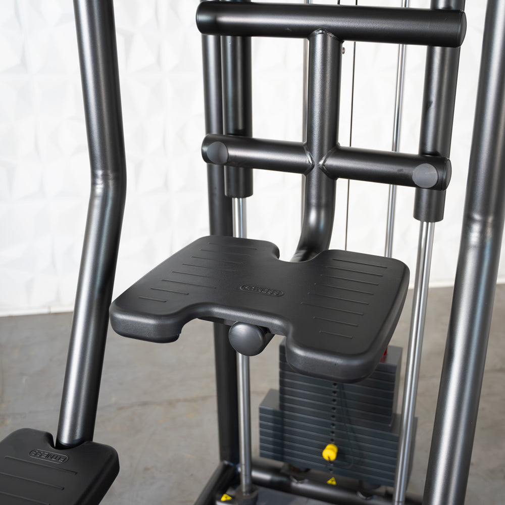Close-up of a black assisted chin/dip machine with a textured foot platform and weight stack.