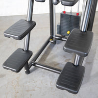 Thumbnail for Close-up of the foot platforms and weight stack of an assisted chin/dip machine.