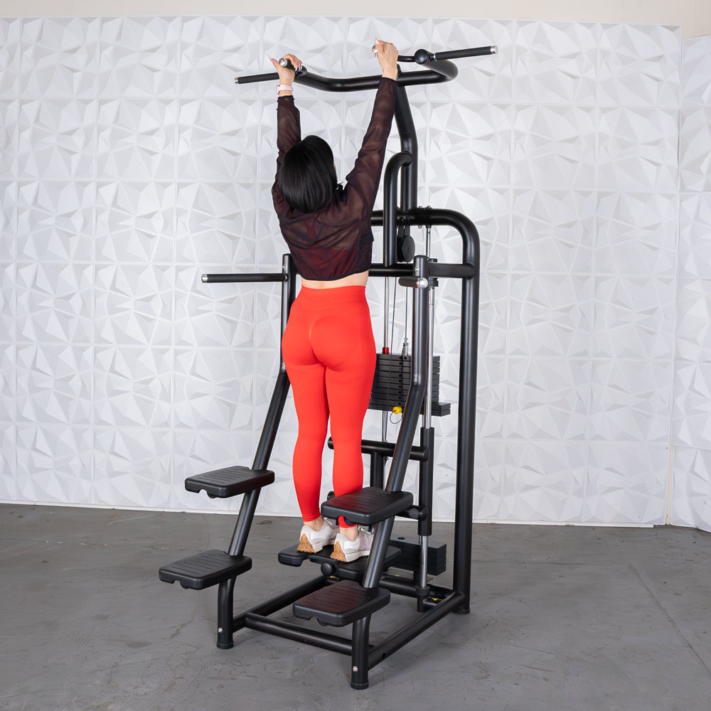 Woman in red leggings using a black assisted chin/dip machine with a weight stack.