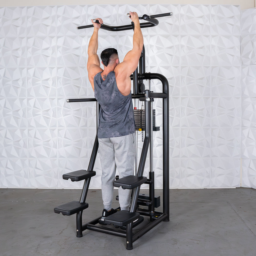 Man using a black assisted chin/dip machine with multiple grip options and weight stack.