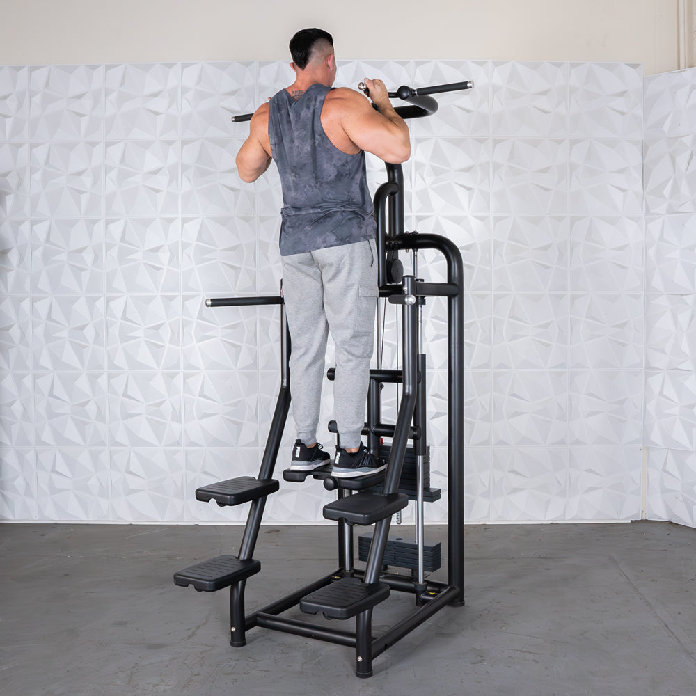 Man using a black assisted chin/dip machine with multiple foot platforms and weight stack.
