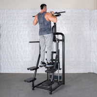 Thumbnail for Man using a black assisted chin/dip machine with multiple foot platforms and weight stack.