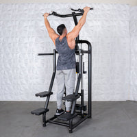 Thumbnail for Man using a black assisted chin/dip machine with multiple foot platforms and an overhead bar.