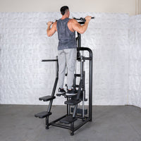 Thumbnail for Man performing pull-ups on a black assisted chin/dip machine with white textured wall in background.