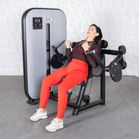 Thumbnail for Woman in red leggings using a black and gray biceps curl machine.