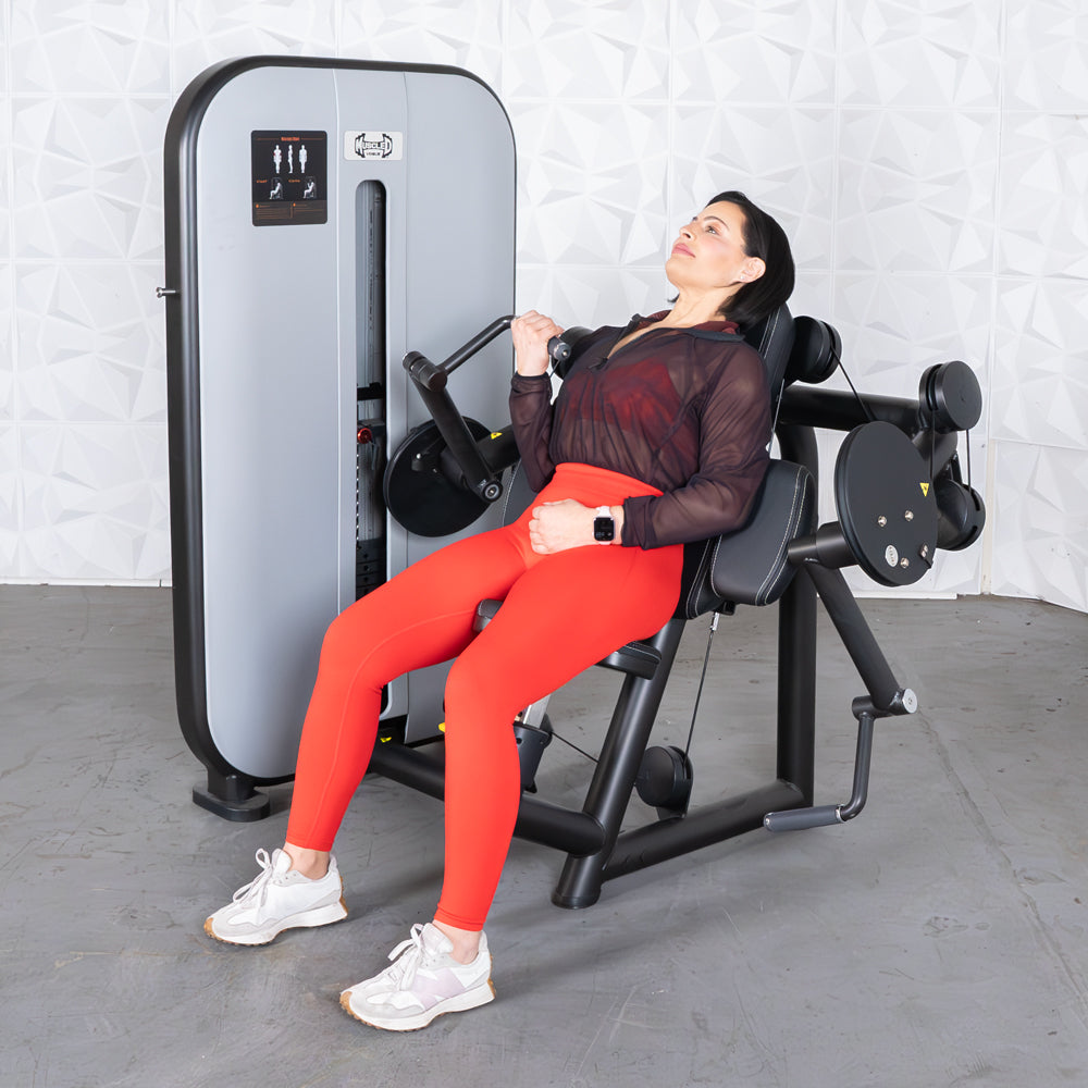 Woman in red leggings using a black and gray biceps curl machine with pin selectorized weights.