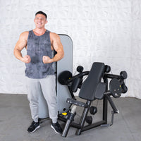Thumbnail for Man flexing next to a black and gray biceps curl machine with a weight stack.