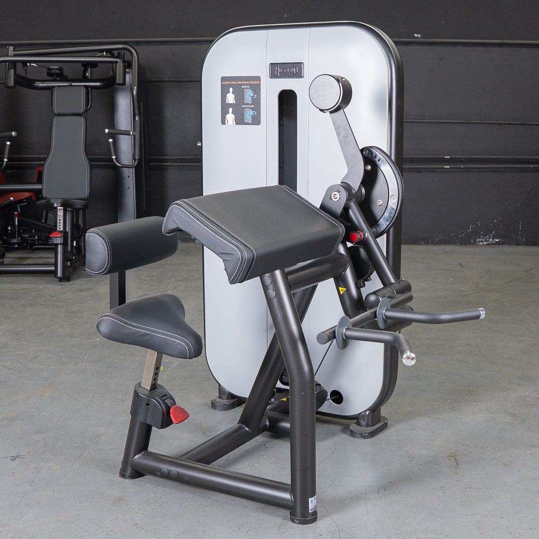 Black and gray biceps/triceps combo gym machine with padded seat and armrest.