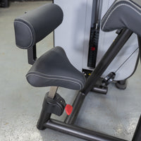 Thumbnail for Close-up of a black padded seat and armrest on a gym machine, with white stitching.