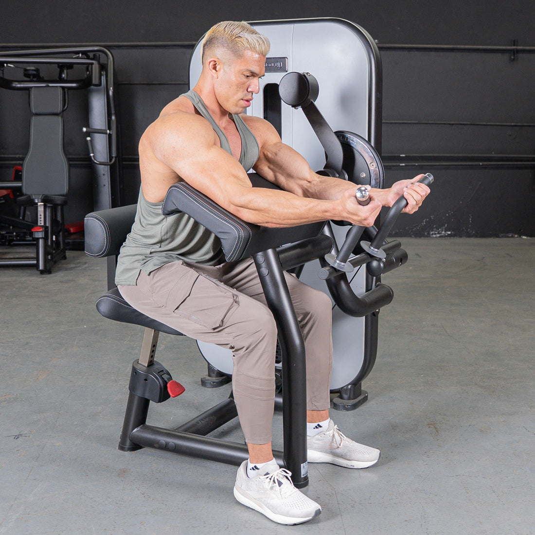 Man using a biceps curl machine in a gym.