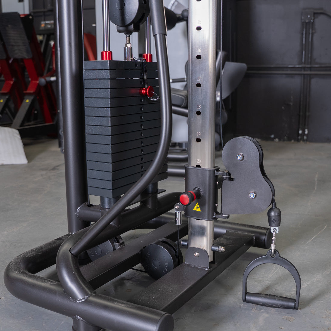 Close-up of a cable crossover machine with weight stack, adjustable pulley, and D-handle attachment.