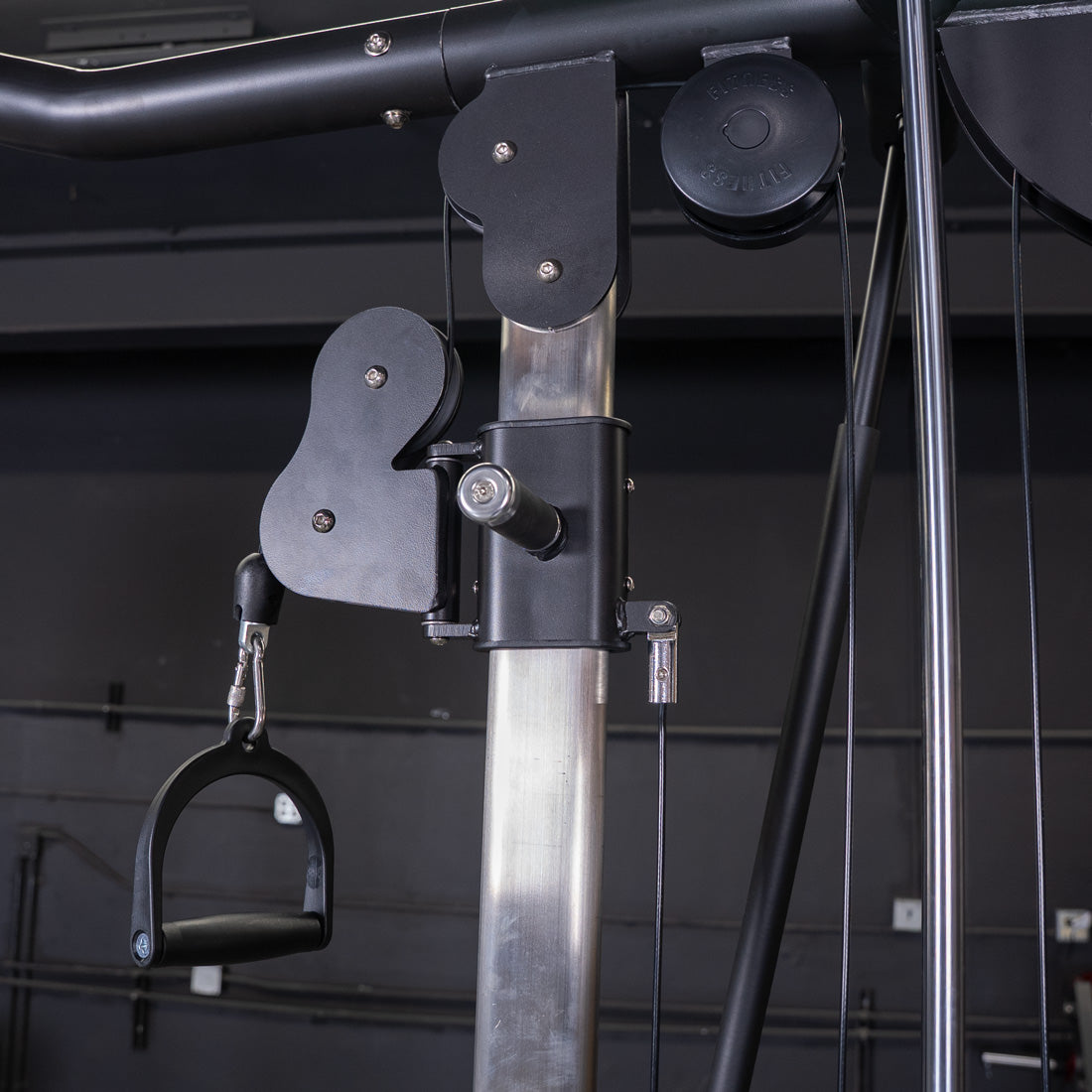 Close-up of a cable crossover machine with a black handle attached to a pulley system.