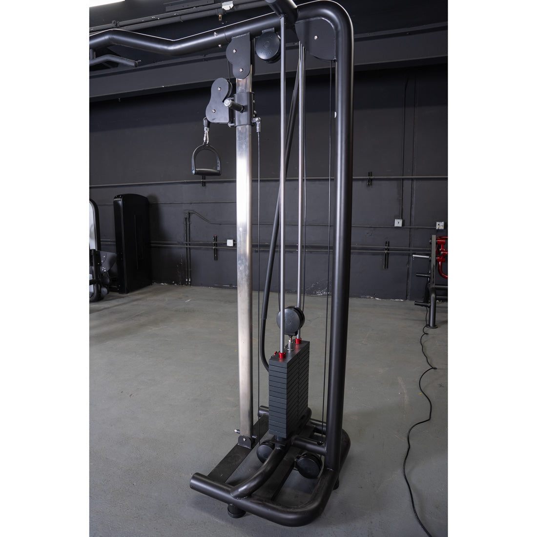 Black cable crossover machine with a D-handle attachment and weight stack in a gym.