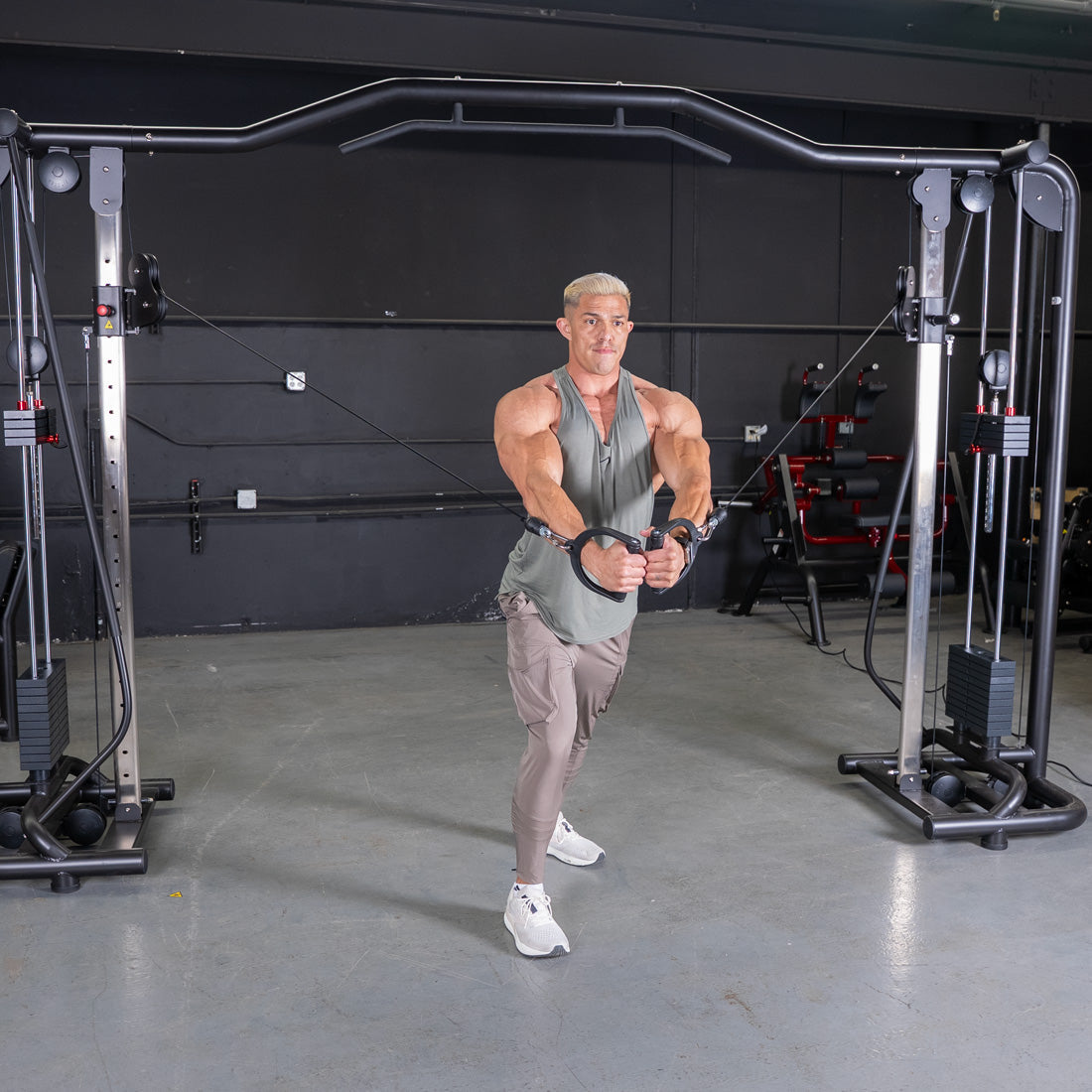 Man performing chest fly exercise on a Vogue Cable Crossover machine in a gym.