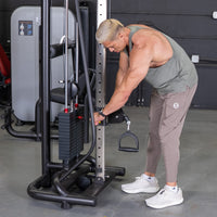 Thumbnail for Man adjusting the pin selector on a cable crossover machine with a D-handle attachment.