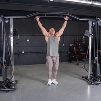 Thumbnail for Muscular man in a gym using a cable crossover machine with a pull-up bar attachment.