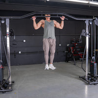 Thumbnail for Man doing pull-ups on a cable crossover machine with weight stacks and pull-up bar.