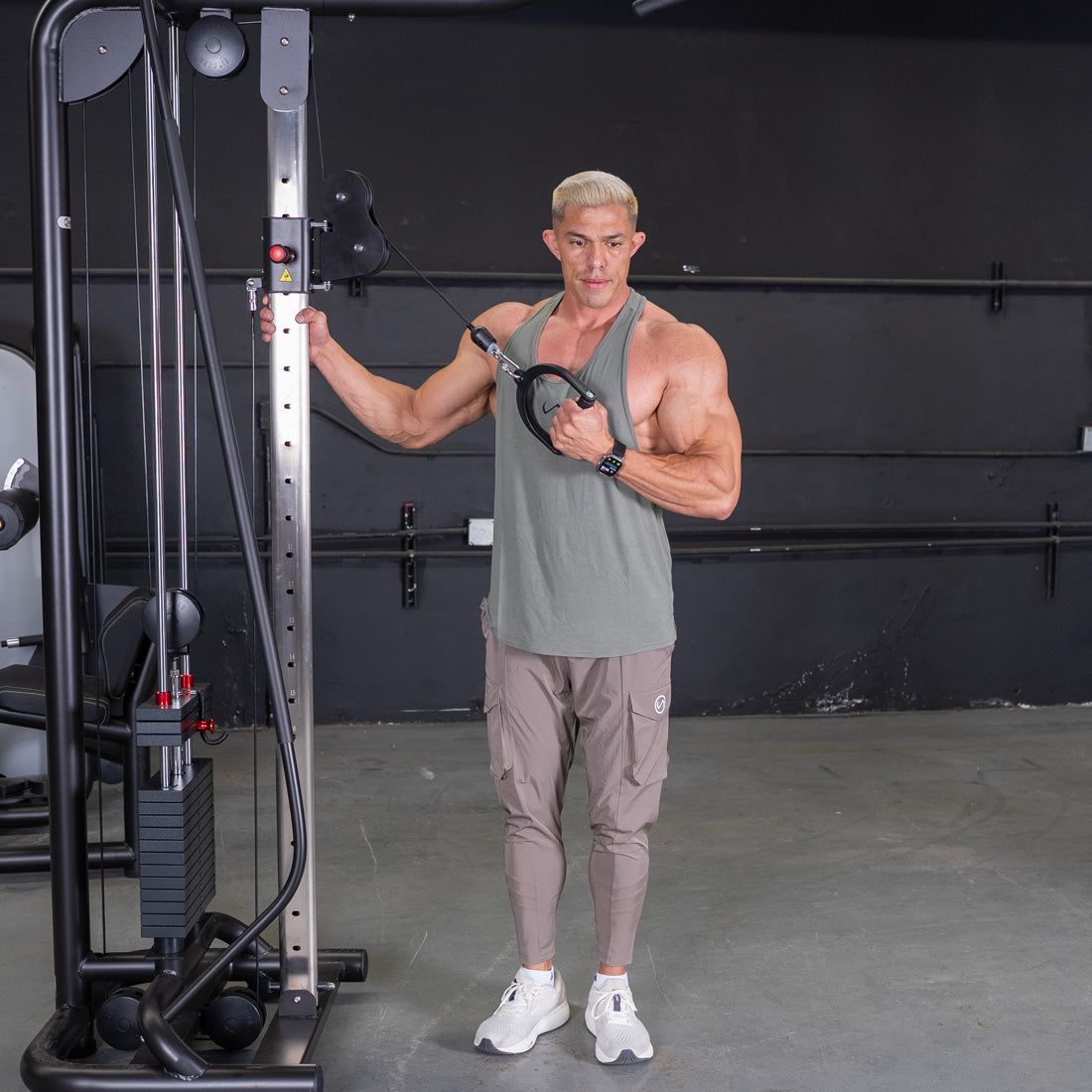 Muscular man in a gym performing a chest fly exercise using a cable crossover machine.