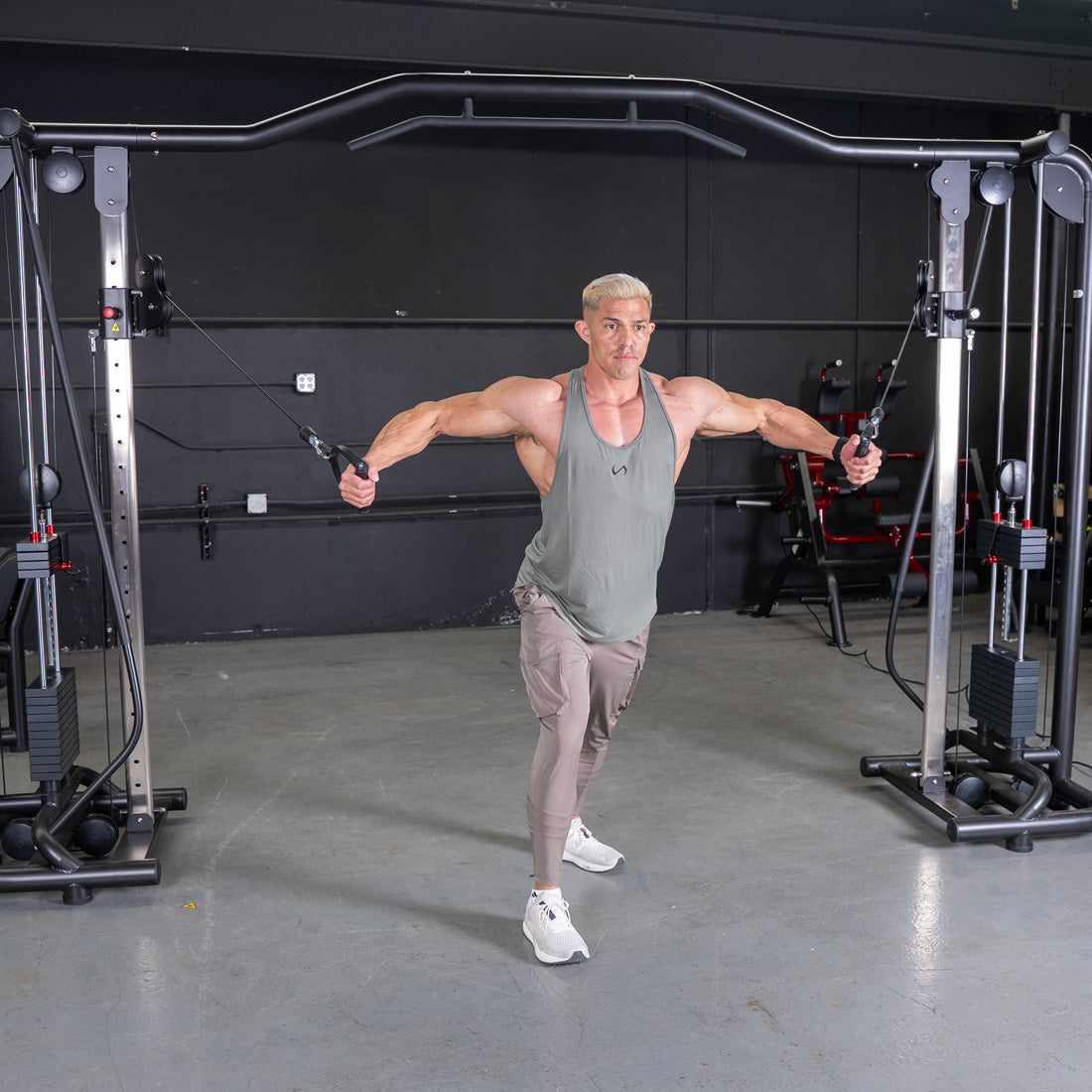 Muscular man performing a cable crossover exercise on a black fitness machine in a gym.