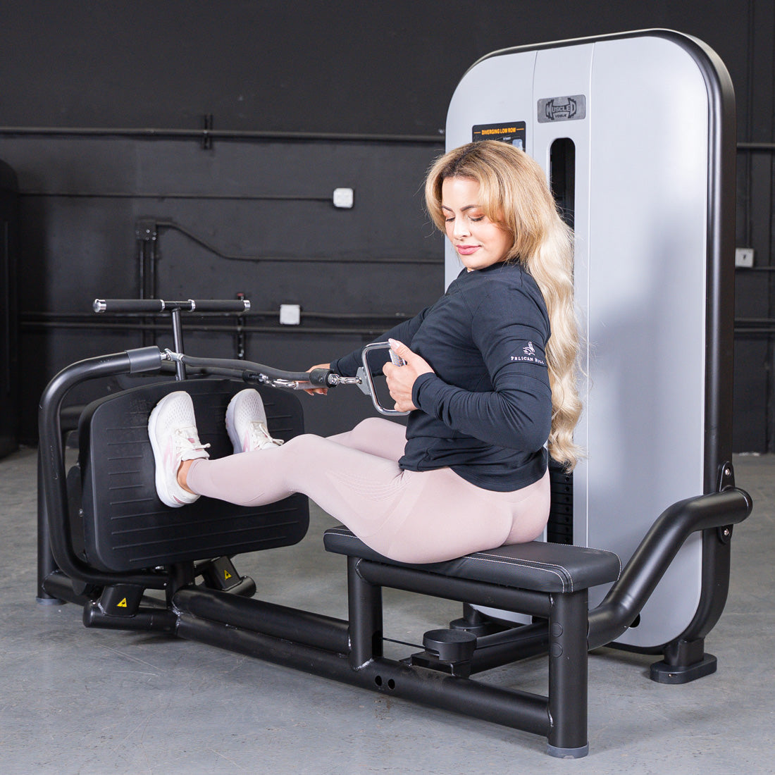 Woman using a low row machine with a pin selectorized weight stack.