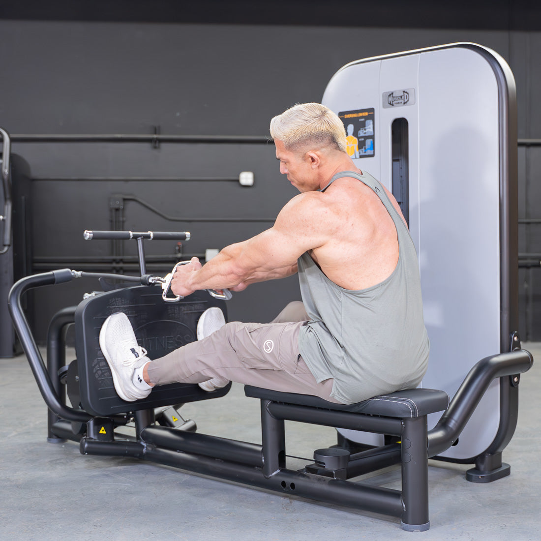Man using a seated low row machine in a gym, pulling the handles towards his torso.