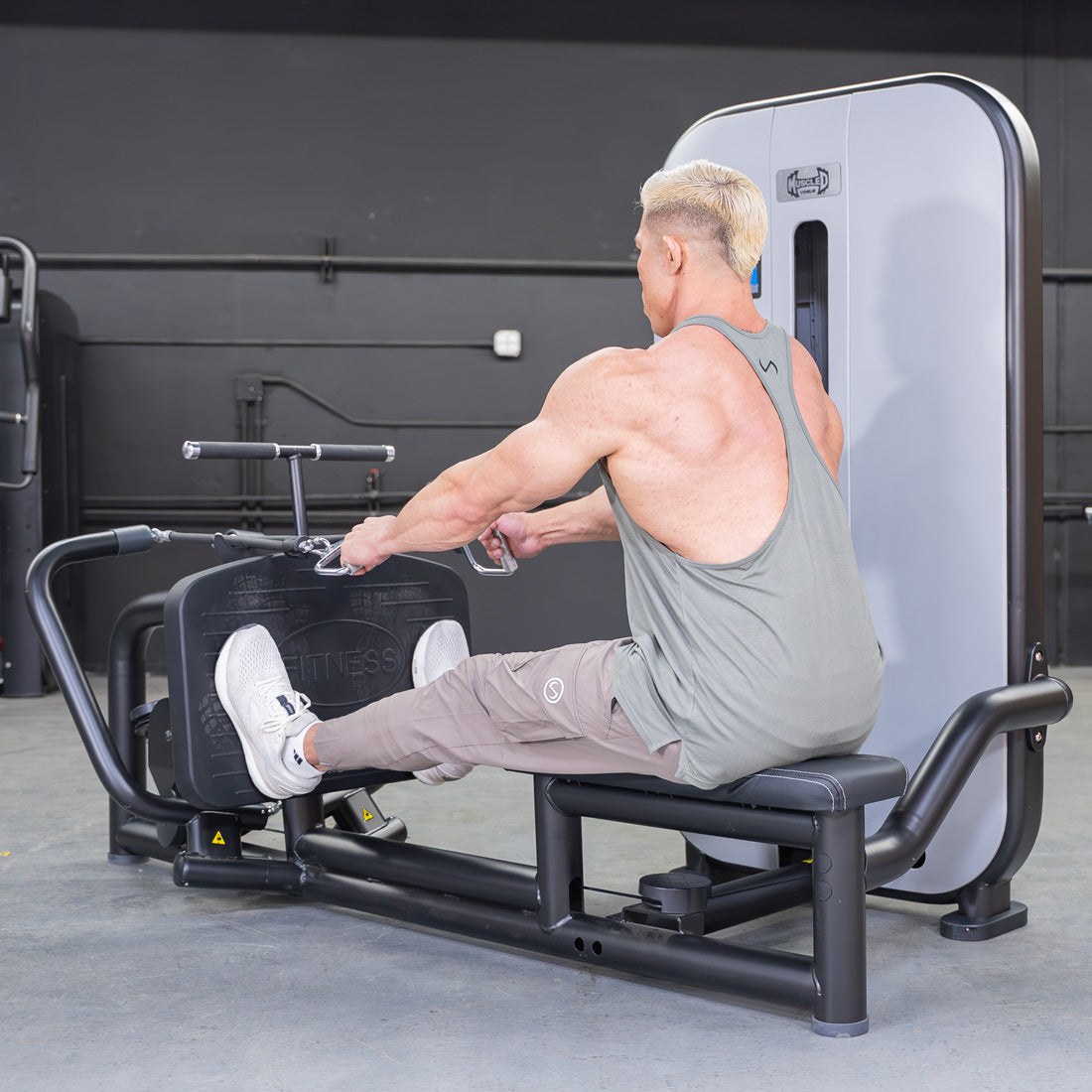 Man using a seated low row machine in a gym.