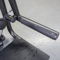 Thumbnail for Close-up of the black textured footplate and padded handle of a glute extension machine.
