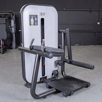 Thumbnail for Gray and black glute extension machine with a padded armrest and foot platform in a gym setting.