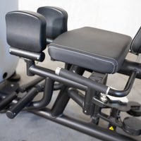 Thumbnail for Close-up of a black gym machine with an adjustable seat, padded leg rests, and handles.