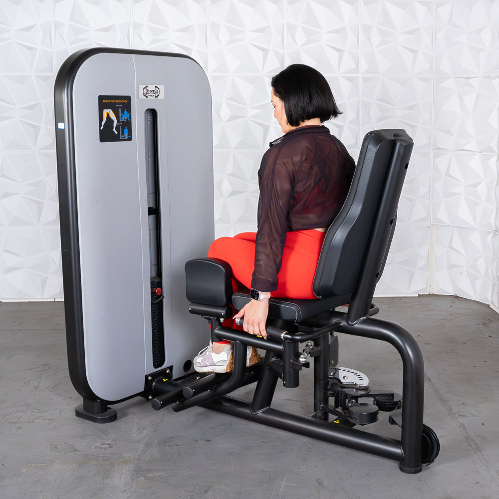 Woman using a gray and black inner/outer thigh workout machine with an adjustable seat.