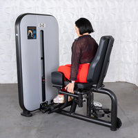 Thumbnail for Woman using a gray and black inner/outer thigh workout machine with an adjustable seat.