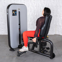 Thumbnail for Woman in red leggings using a gray and black inner/outer thigh workout machine.