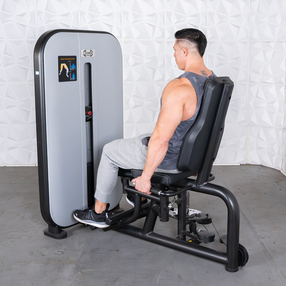 Man using a grey and black inner/outer thigh workout machine with an adjustable seat.