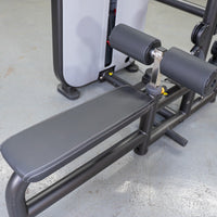Thumbnail for Close-up of a black gym bench with white stitching and leg pads, part of a gray fitness machine.