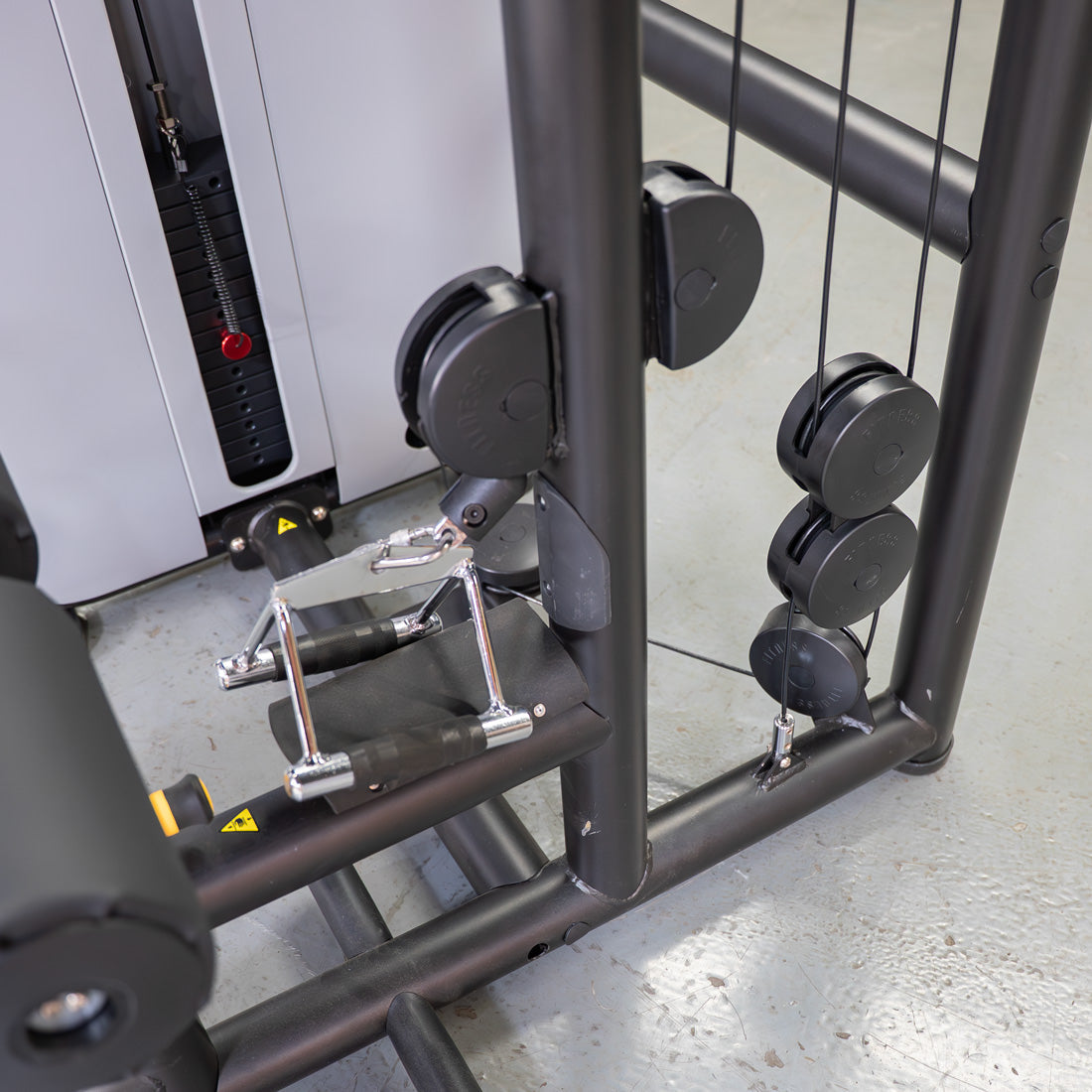 Close-up of a lat/low row machine showing the weight stack, cable pulleys, and a chrome handle.