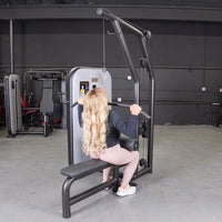 Thumbnail for Woman with long blonde hair using a black and gray lat pulldown/low row machine in a gym.