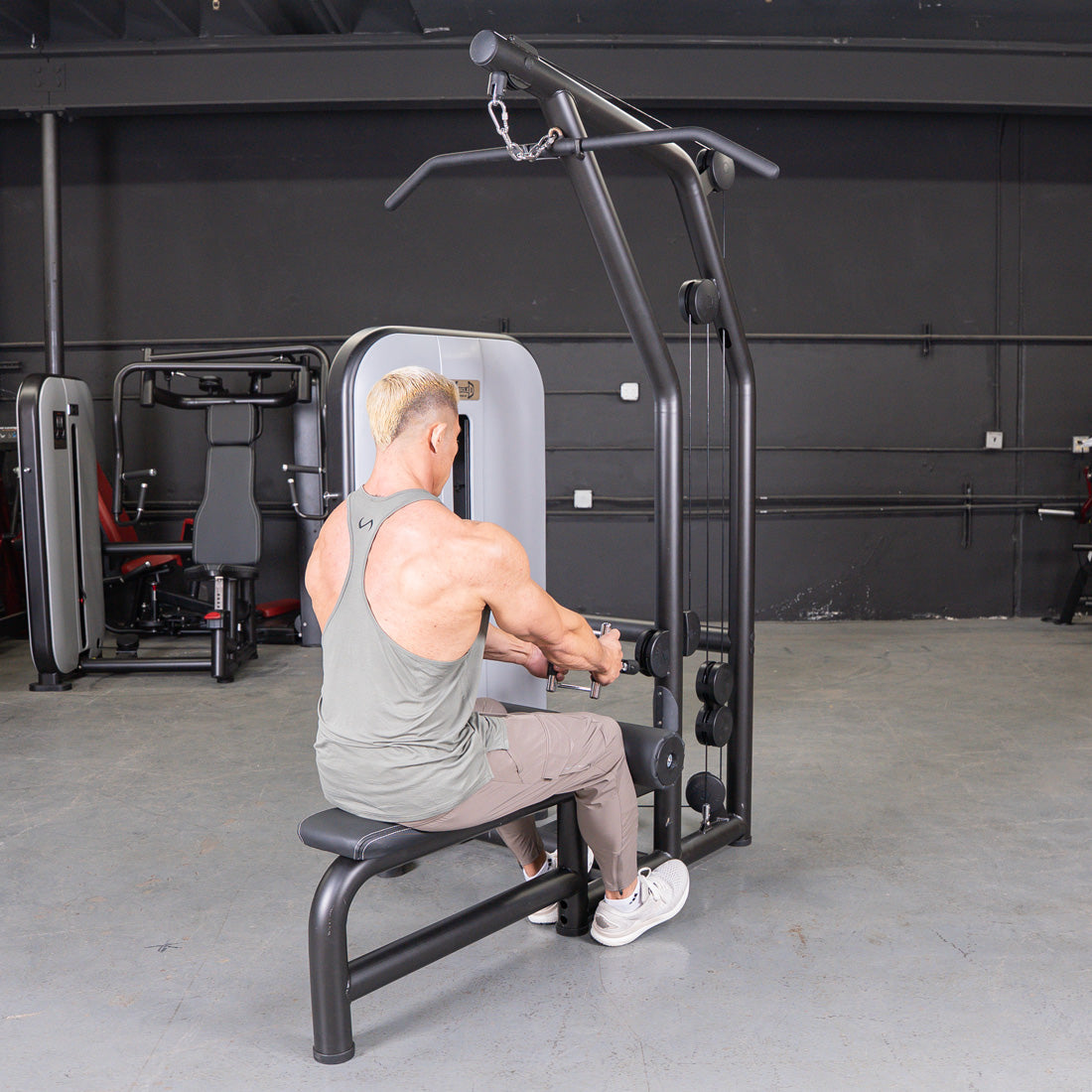 Man performing a low row exercise on a black lat/low row machine in a gym.