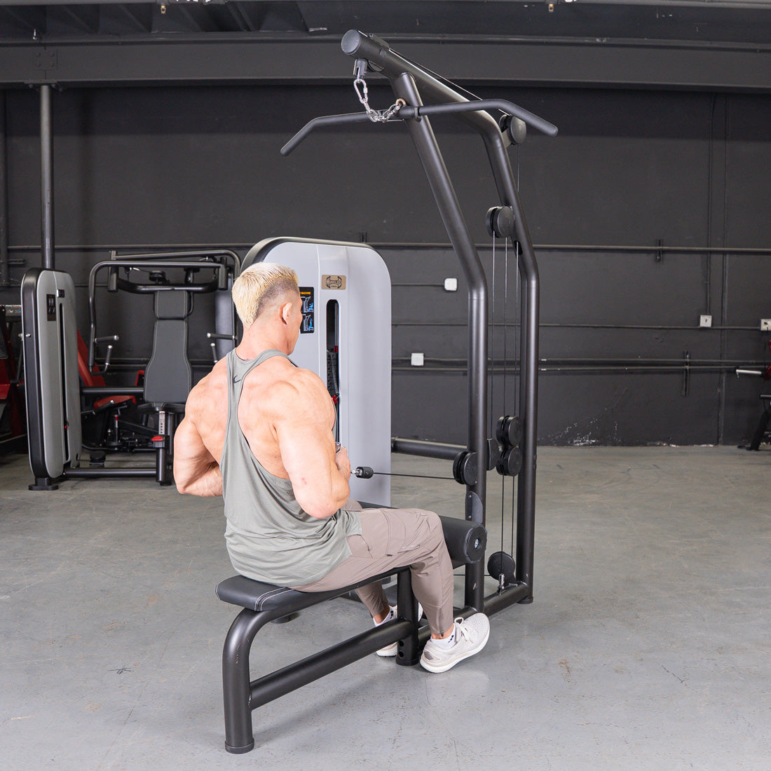 Man performing a low row exercise on a black lat/low row machine with an adjustable seat.