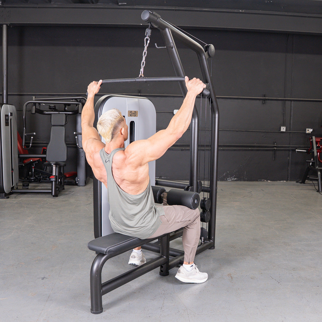 Man using a black lat pulldown and low row machine with an adjustable seat and pin selectorized weights.