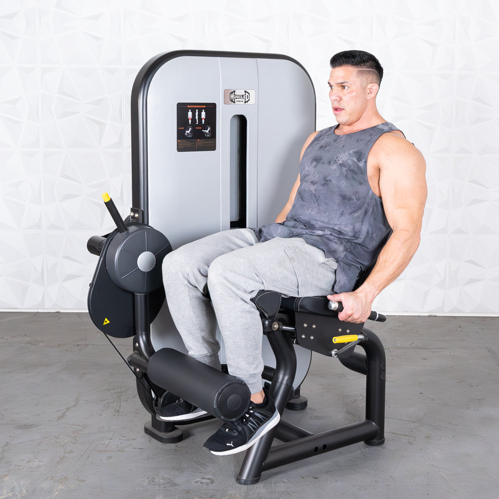 Man using a gray and black leg extension machine with a pin selectorized weight stack.