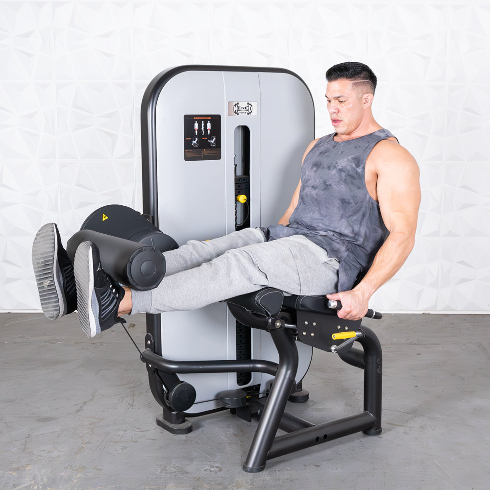 Man using a leg extension machine, extending his legs forward.