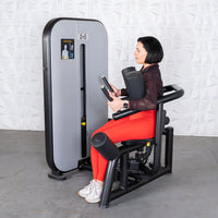 Thumbnail for Woman in red leggings using a gray and black rotary torso machine.