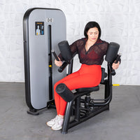 Thumbnail for Woman in red leggings using a black and gray rotary torso fitness machine.