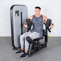 Thumbnail for Man using a gray and black rotary torso machine with padded arm and leg rests.