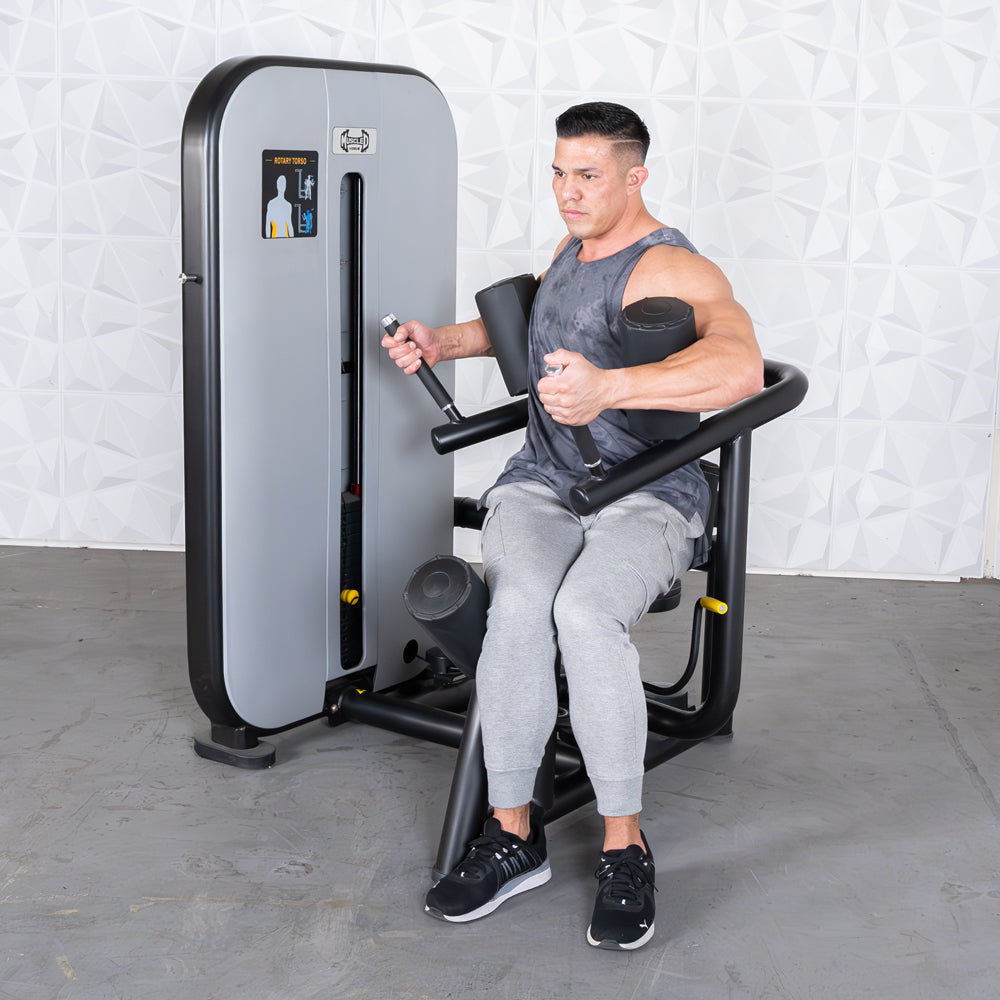 Man using a gray and black rotary torso machine, engaging his core.