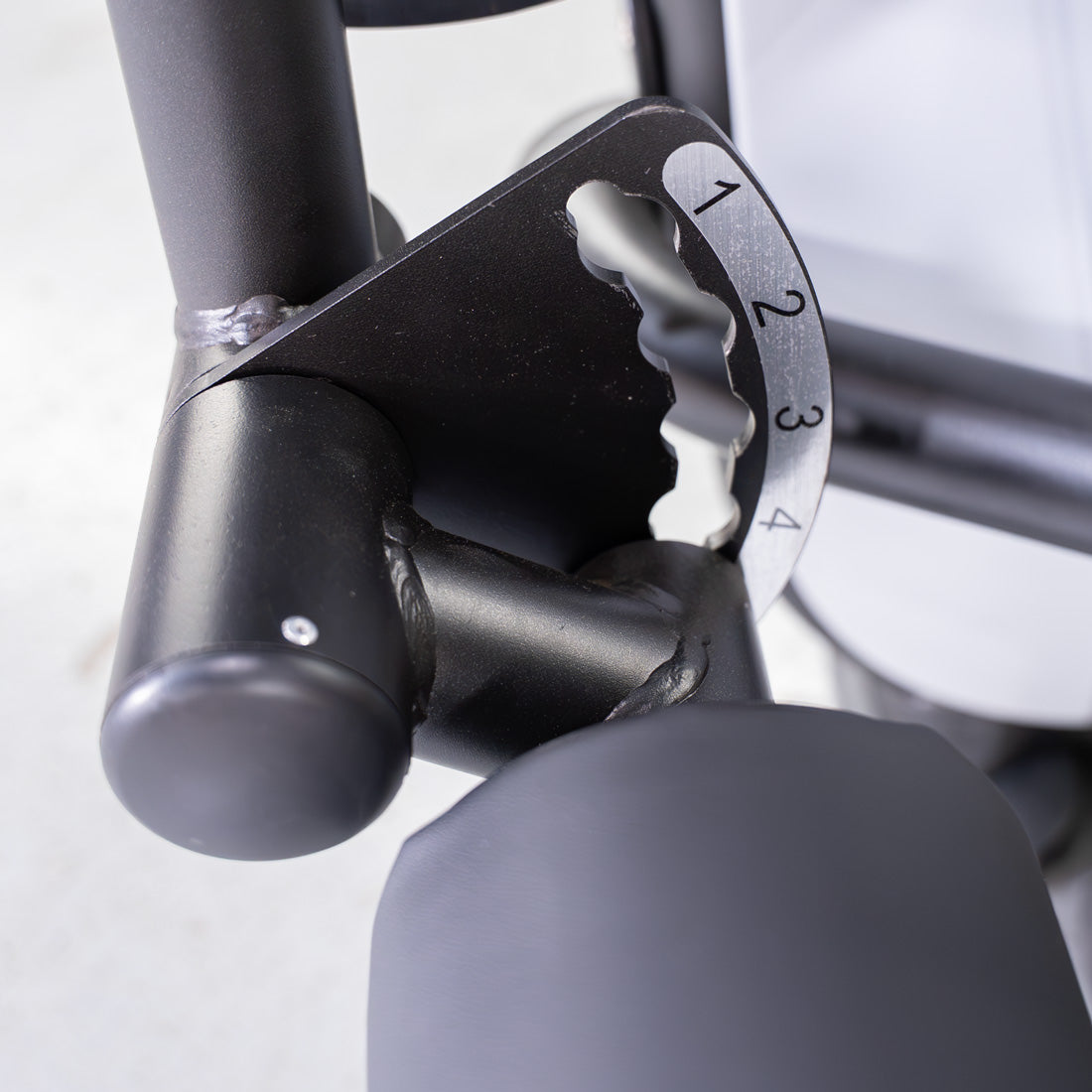 Close-up of a leg curl machine's pin selectorized adjustment mechanism with numbers 1-4 visible.