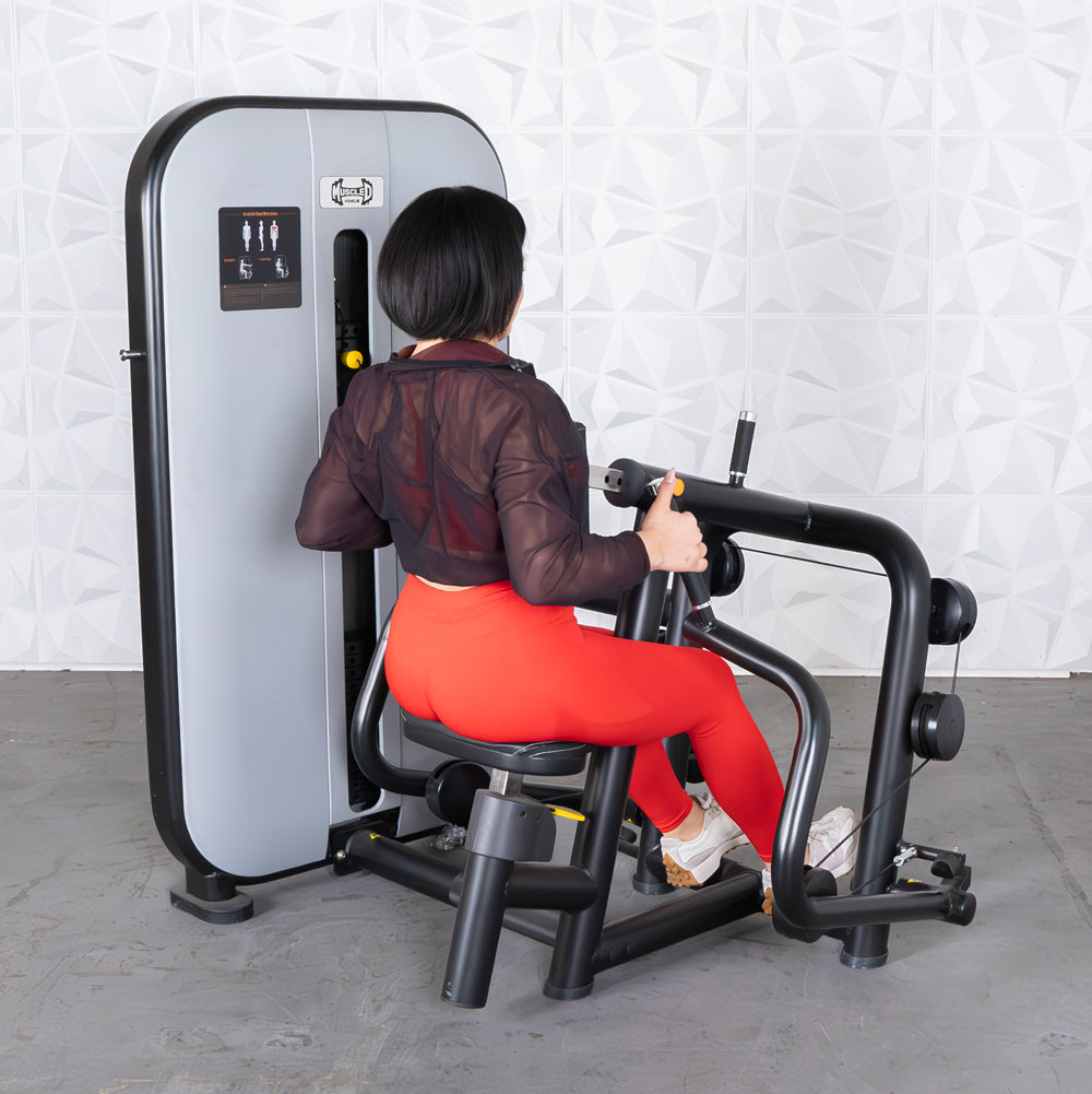 Woman in red leggings using a seated row machine with an adjustable seat and pin selectorized weights.