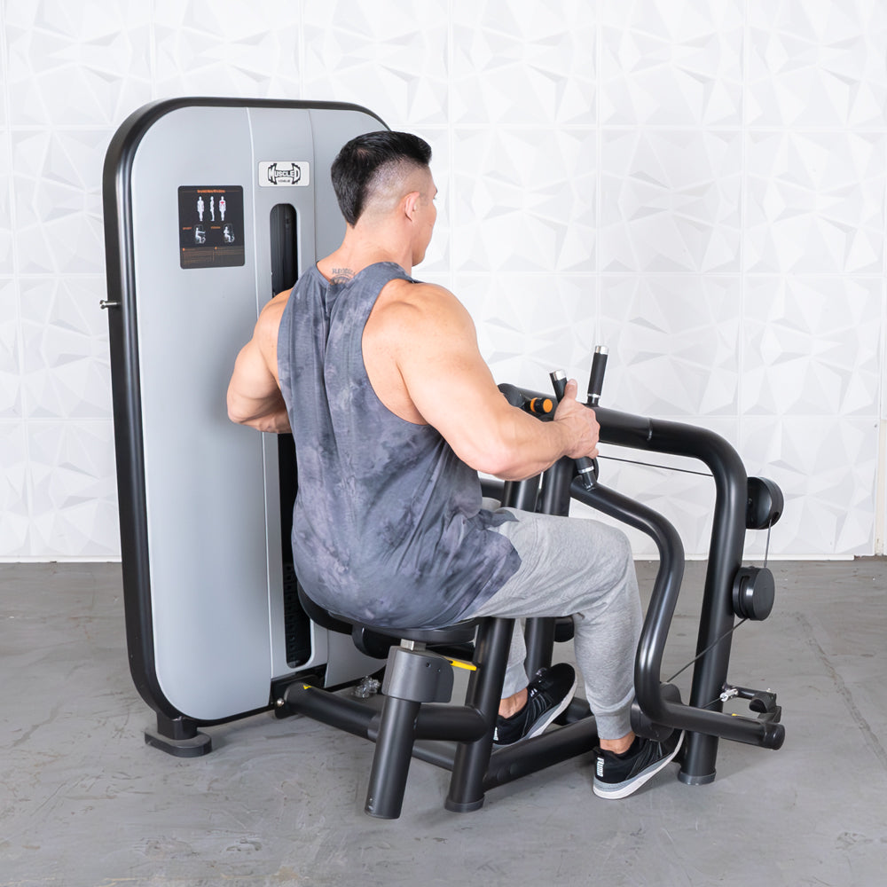Man using a Vogue Seated Row machine, pulling handles towards his torso.