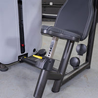 Thumbnail for Close-up of a shoulder press machine's adjustable black seat, yellow pin selector, and weight stack.