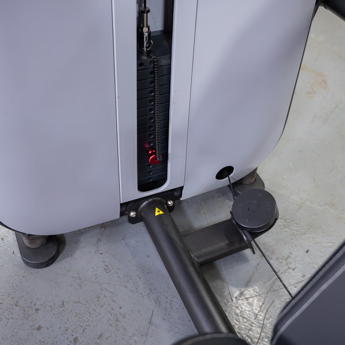 Close-up of a weight stack with a red pin selector on a grey fitness machine.